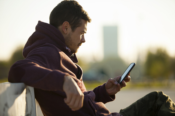 Handsome Man In Hoodie Holding and Looking At Mobile Smart Phone Outdoors - How to know if an Aquarius man doesn’t like you