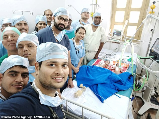 The baby girls - who were three days old at the time of the procedure - weighed just 7lbs between them and were joined at the stomach (pictured: the selfie after the operation, with Dr Vaibhav Pandey, who led the surgery, at the front)