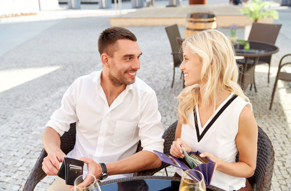 happy couple with wallet and wine glasses paying bill at restaurant