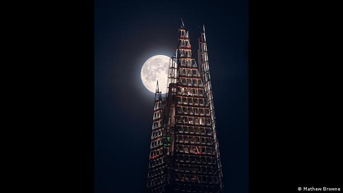 The bright orb of the moon peeks out from the jagged top of the Shard skyscraper. (Photo: Mathew Browne).