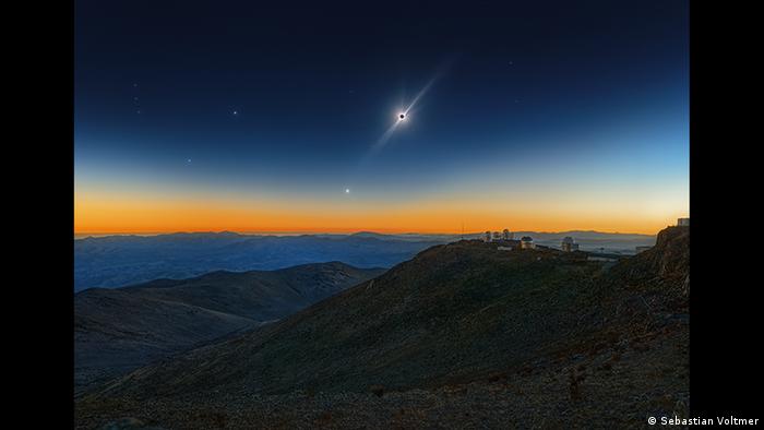 A bright solar eclipse shines above a colorful sunset in the mountains. (Photo: Sebastian Voltmer).