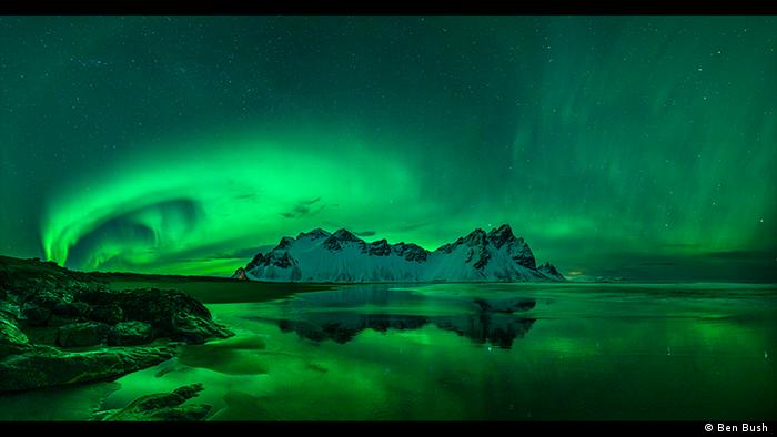 Green light swirls in this photo of arctic waters and snow-capped rock formations (Photo: Ben Bush ).