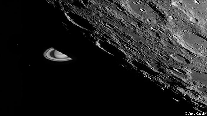 Ringed Saturn peeks out from behind the large, pockmarked surface of the moon. (Ph
oto: Andy Casely).
